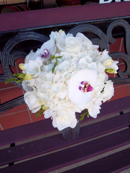 Phalaenopsis orchids, white roses, fragrant freesia and white hydrangea.