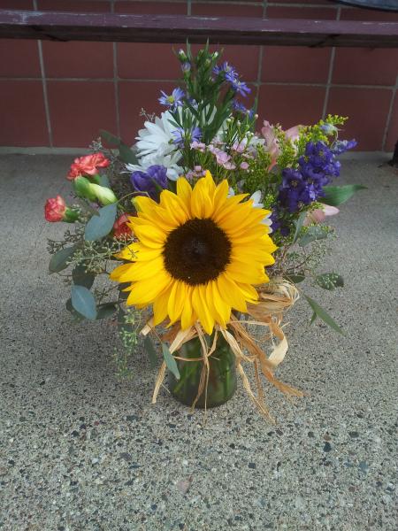  Designed with sunflowers, monte casino, orange mini carnations and a variety of other flowers, tied off with raffia.
