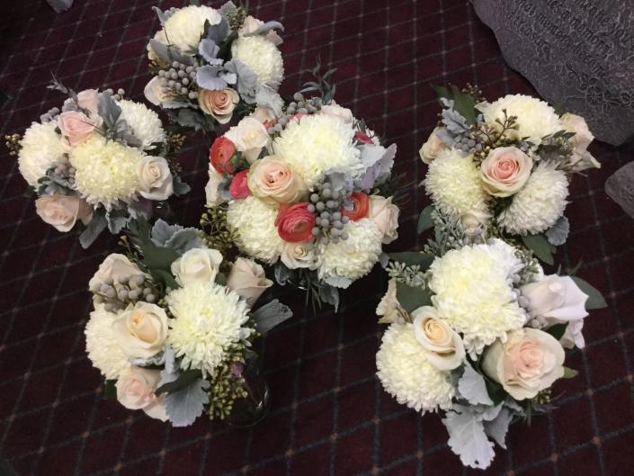 Ivory and blush roses, ranunculus, football mums, Bruneian berries and dusty miller.