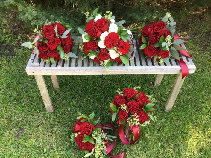 Bride and bridesmaids bouquets, deep red "heart" roses, white roses and a variety of greenery.
