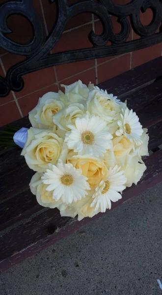  Pale yellow roses, ivory minature gerbera daisies accented with white satin ribbon.