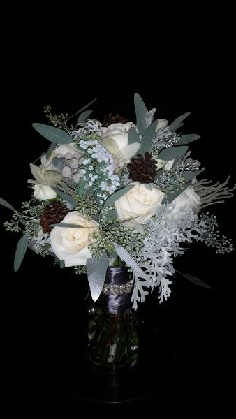 Ivory roses, berzillia berries, dusty miller, seeded eucalyptus (sprayed a hint of silver), minature pine cones tied off with satin pewter ribbon and a crystal wrap.