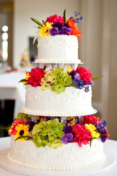 The vibrant wedding flowers compliment the white layers of this traditional wedding cake.