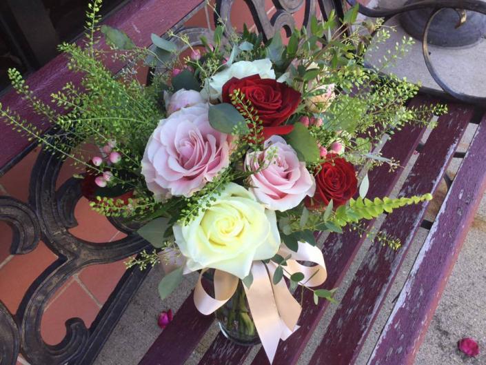 This natural looking bouquet was designed with black majic, light pink, white and ivory roses. It also has light pink hypericum berries, penny cress, ferns and eucalyptus.