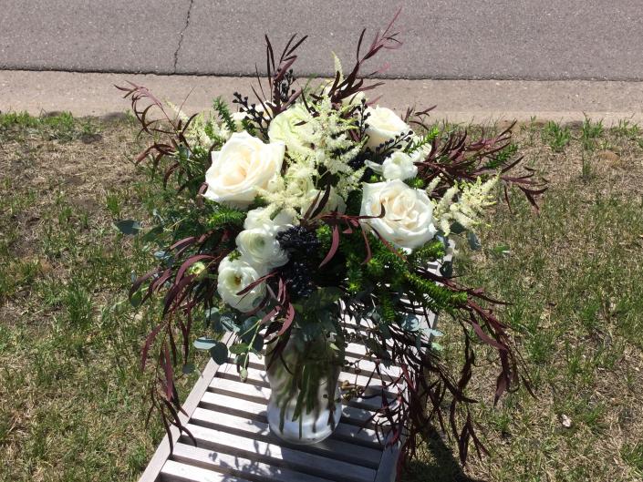 White ranunculus, roses, astilbe and lush green accents.