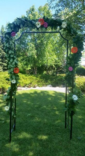 Arbor decorated with fresh mixed greenery and gerber daisies.