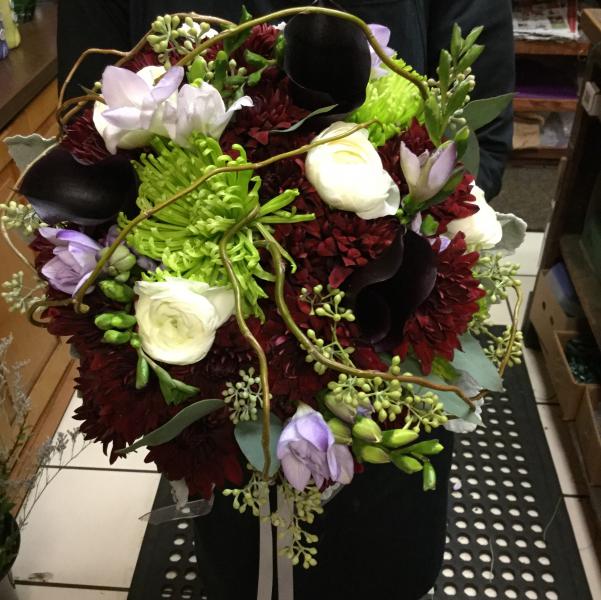 Burgundy dahlias, white ranunculus, lavender freesia, green spider mums, seeded eucalyptus all accented with curly willow.