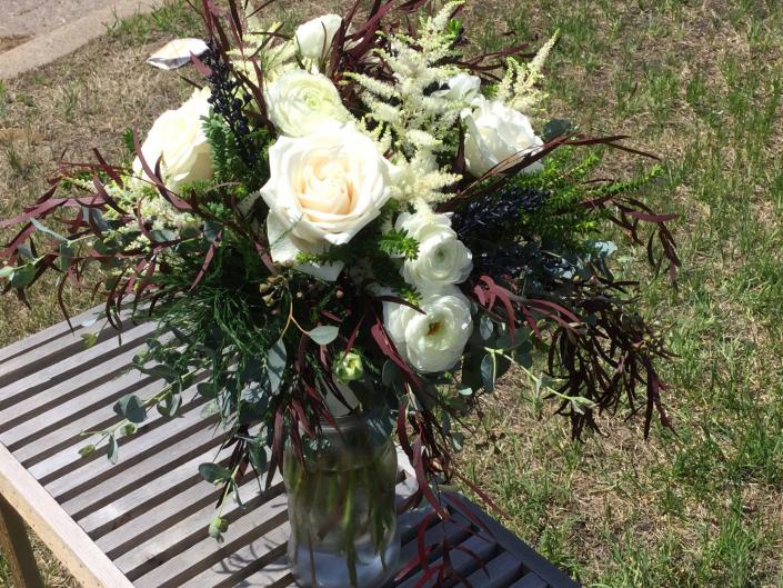 White roses and ranunculus, astilbe and a variety of eucalyptus.