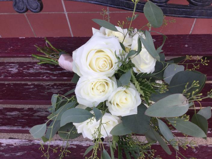 Large and mini fragrant white roses, a variety of eucalyptus and leatherleaf fern, tied off with champagne ribbon.