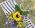 Yellow sunflowers, lavender statice and larkspur, yellow alstromeria, ladies mantle and white waxflower.