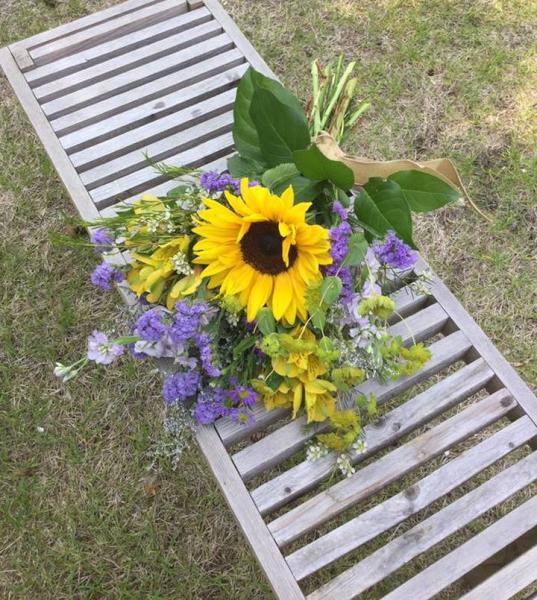 Yellow sunflowers, lavender statice and larkspur, yellow alstromeria, ladies mantle and white waxflower.