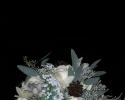 Ivory roses, berzillia berries, dusty miller, seeded eucalyptus (sprayed a hint of silver), minature pine cones tied off with satin pewter ribbon and a crystal wrap.